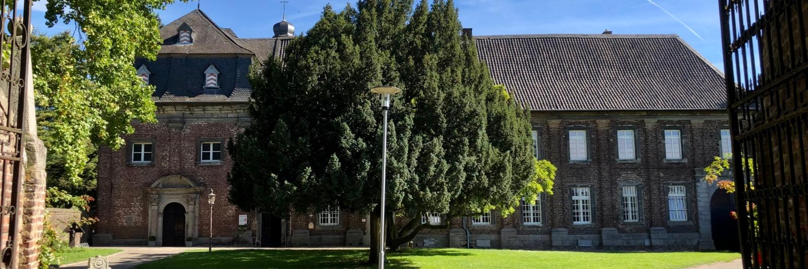 Das Nikolauskloster in Jüchen, es ist deutlich mehr als ein Kloster: Es ist Herberge, Gasthaus, Notunterkunft, Oase, Treffpunkt, Kaffeepausenort und vieles, vieles mehr. All die Arbeit, die damit verbunden ist, können die Brüder vor Ort nicht alleine stemmen - sie sind auf Ehrenamtliche angewiesen und suchen immer wieder Menschen, die im Kleinen oder Großen im Kloster helfen. Das Foto zeigt das Nikolauskloster in Jüchen. Bernd Hamer erstellte es für Himmel und Erde im Rhein-Kreis Neuss für das Familienforum Edith Stein.