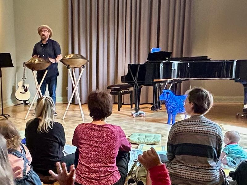 Babys und Eltern lauschen dem Konzert von Stefan Pelzer-Florack, der auf einer Handpan spielt.