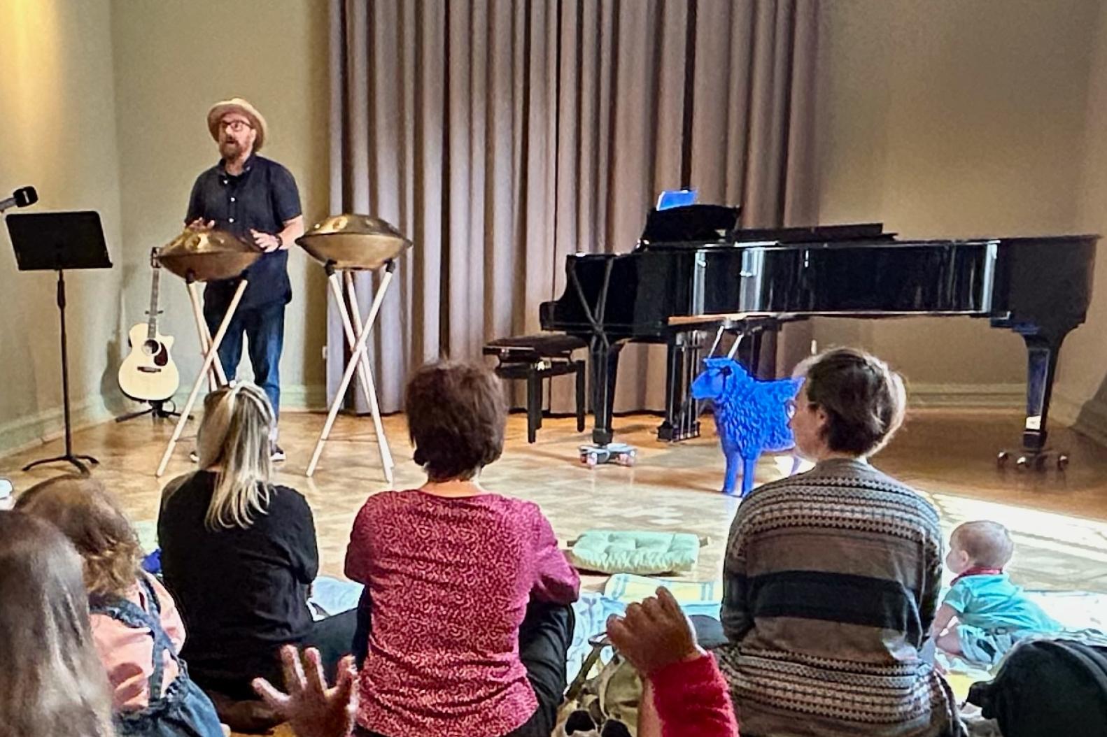 Babys und Eltern lauschen dem Konzert von Stefan Pelzer-Florack, der auf einer Handpan spielt.