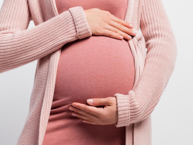 Eine schwangere Frau hält ihre Hände um Ihren Bauch.