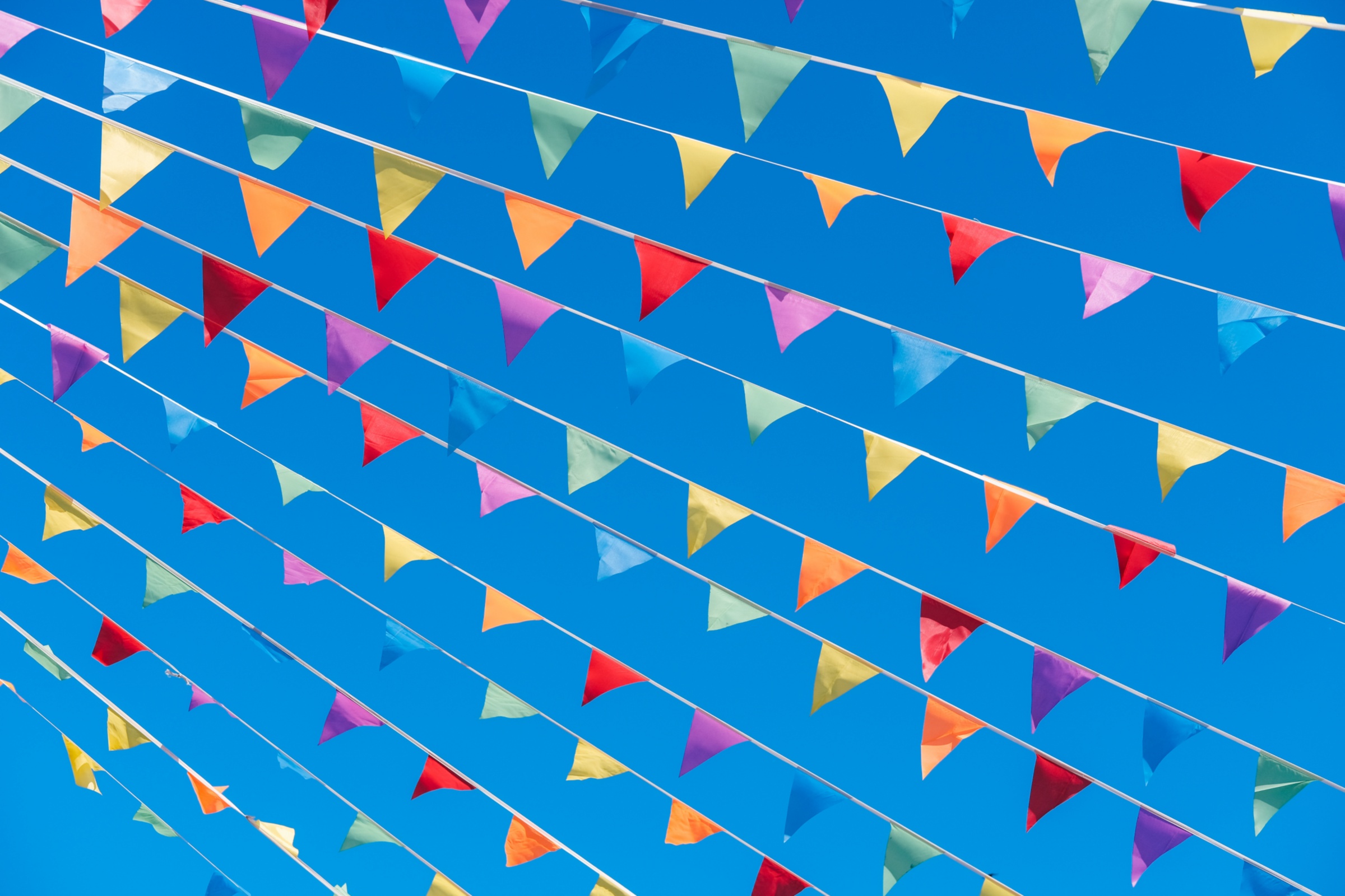 Bunte Wimpelketten vor einem blauen Himmel.