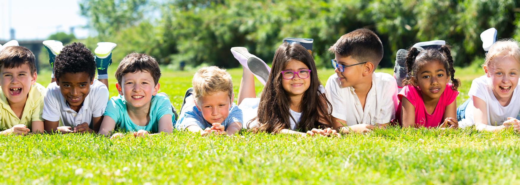 Happy team of friends children resting on grass together in park