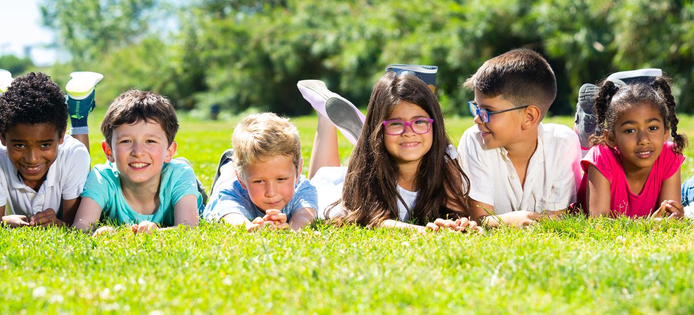 Happy team of friends children resting on grass together in park