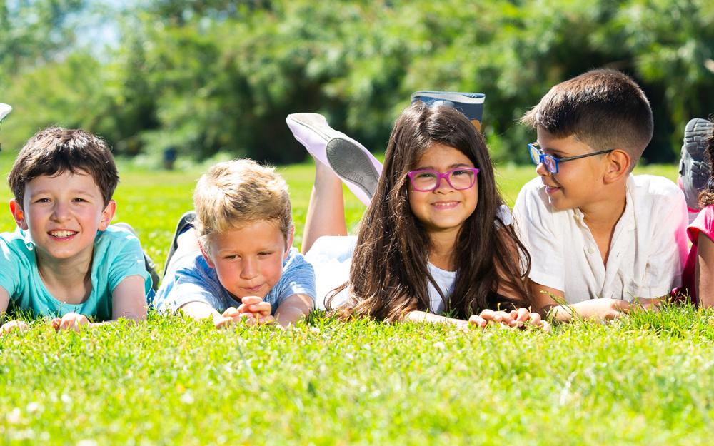 Happy team of friends children resting on grass together in park