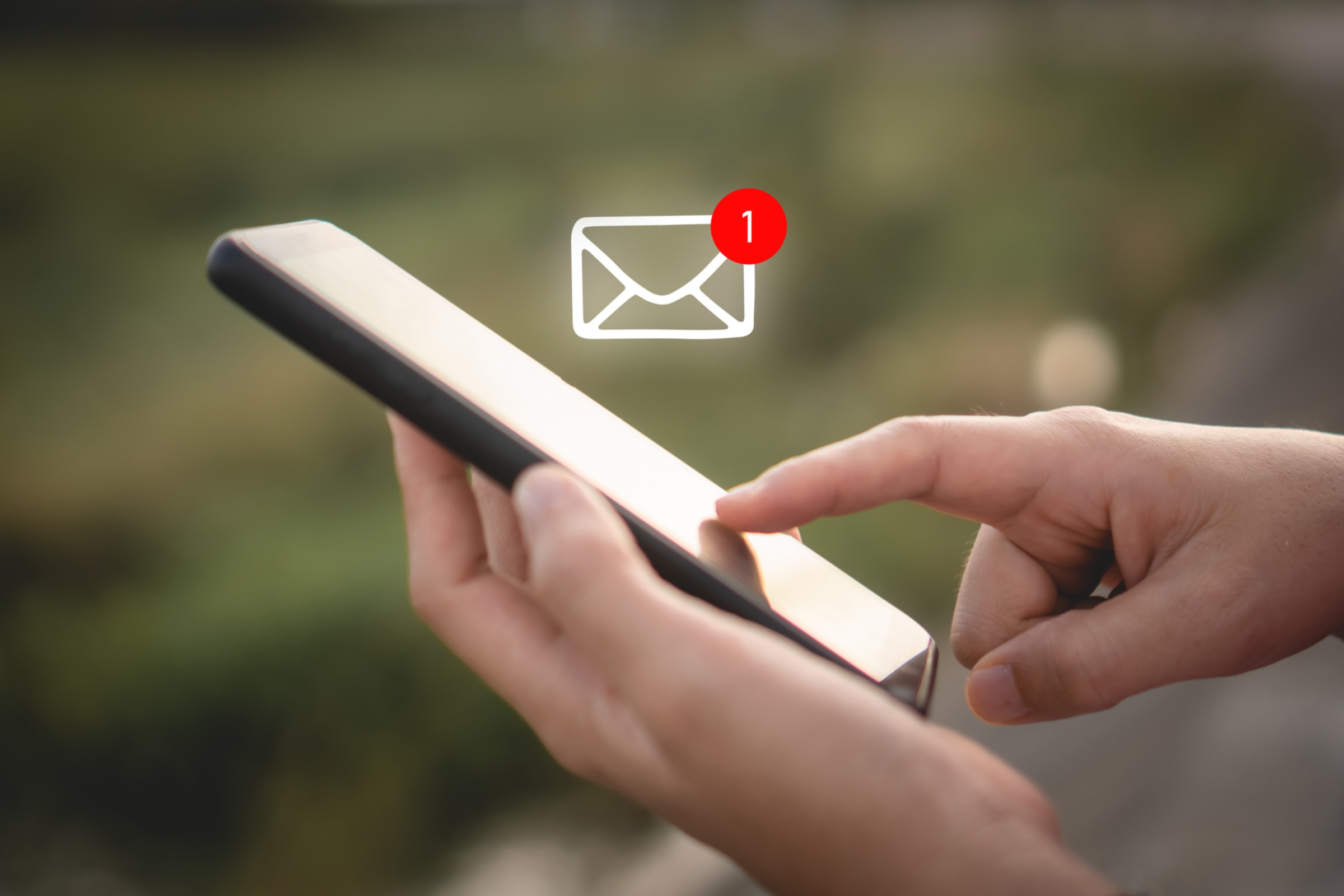 Eine Frauenhand berührt das Display eines Smartphones. Ein Icon für den Erhalt einer E-Mail ist über dem Smartphone zu sehen.